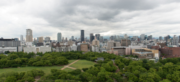 Aerial view of moat around castle park, Osaka business district and spectacular mountains surrounding the city from Osaka Castle.