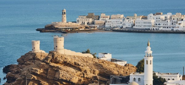 Lighthouse, watchtowers and white houses of traditional architecture of old town Sur in Sultanate of Oman.