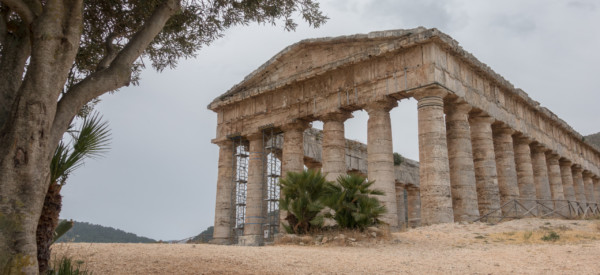 The ruin of the old Roman temple with an olive tree on a cloudy day in Segesta, Sicily, Italy.