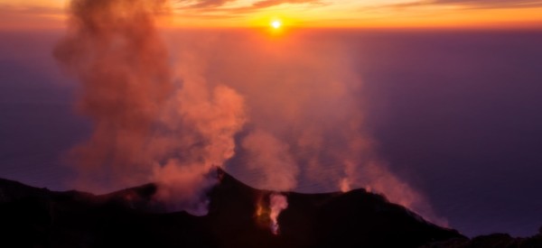 Smoking erupting volcano on Stromboli island at colorful sunset, Sicily, Italy