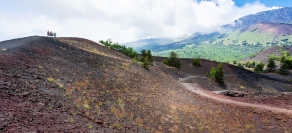 travel to Italy - tourists walk on ridge between old crater of Etna volcano in Sicily