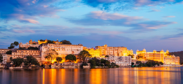 Rajasthan indian tourist landmark - Udaipur City Palace complex in the evening twilight with dramatic sky - panoramic view. Udaipur, India