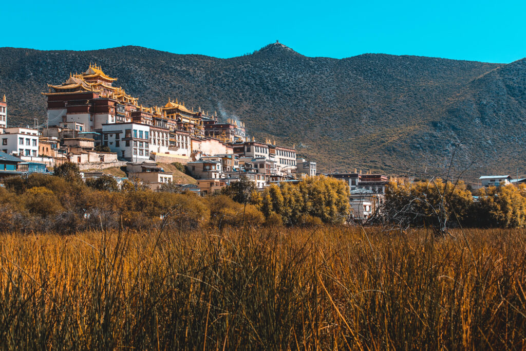 Weite Sicht auf ein grünes Gebirgstal in Bhutan unter blauem Himmel.